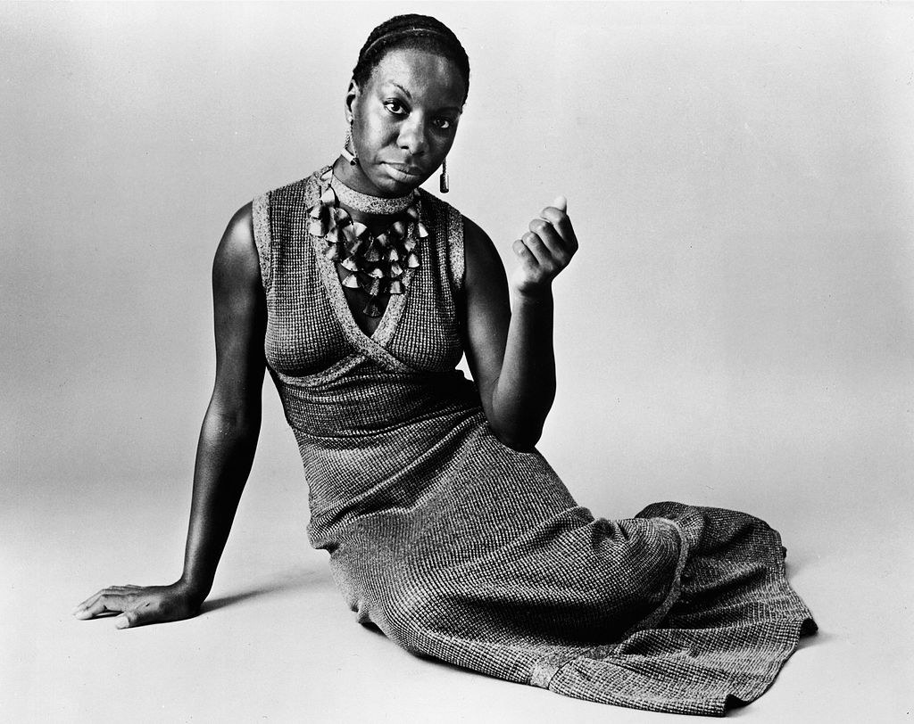 Black and white photograph of Nina Simone posing on a floor 