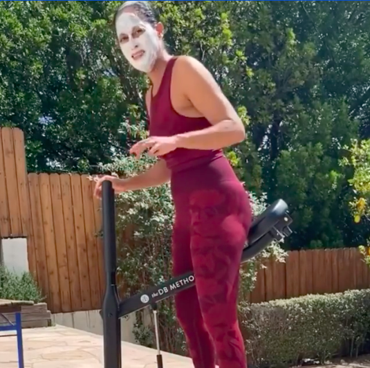 Tracee Ellis Ross with a face mask straddling an exercise machine outside while looking scared