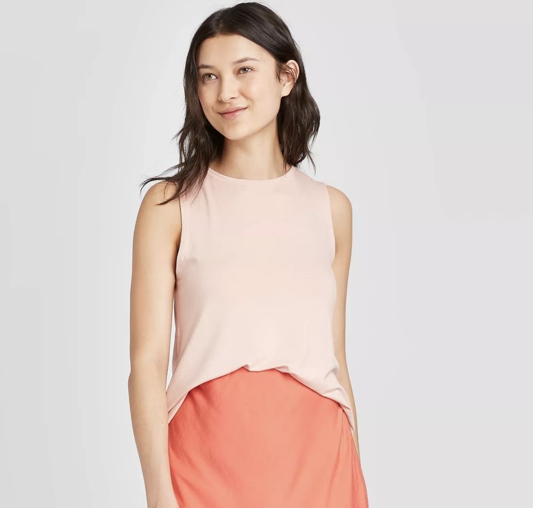 Model wears pink tank with coral skirt. 
