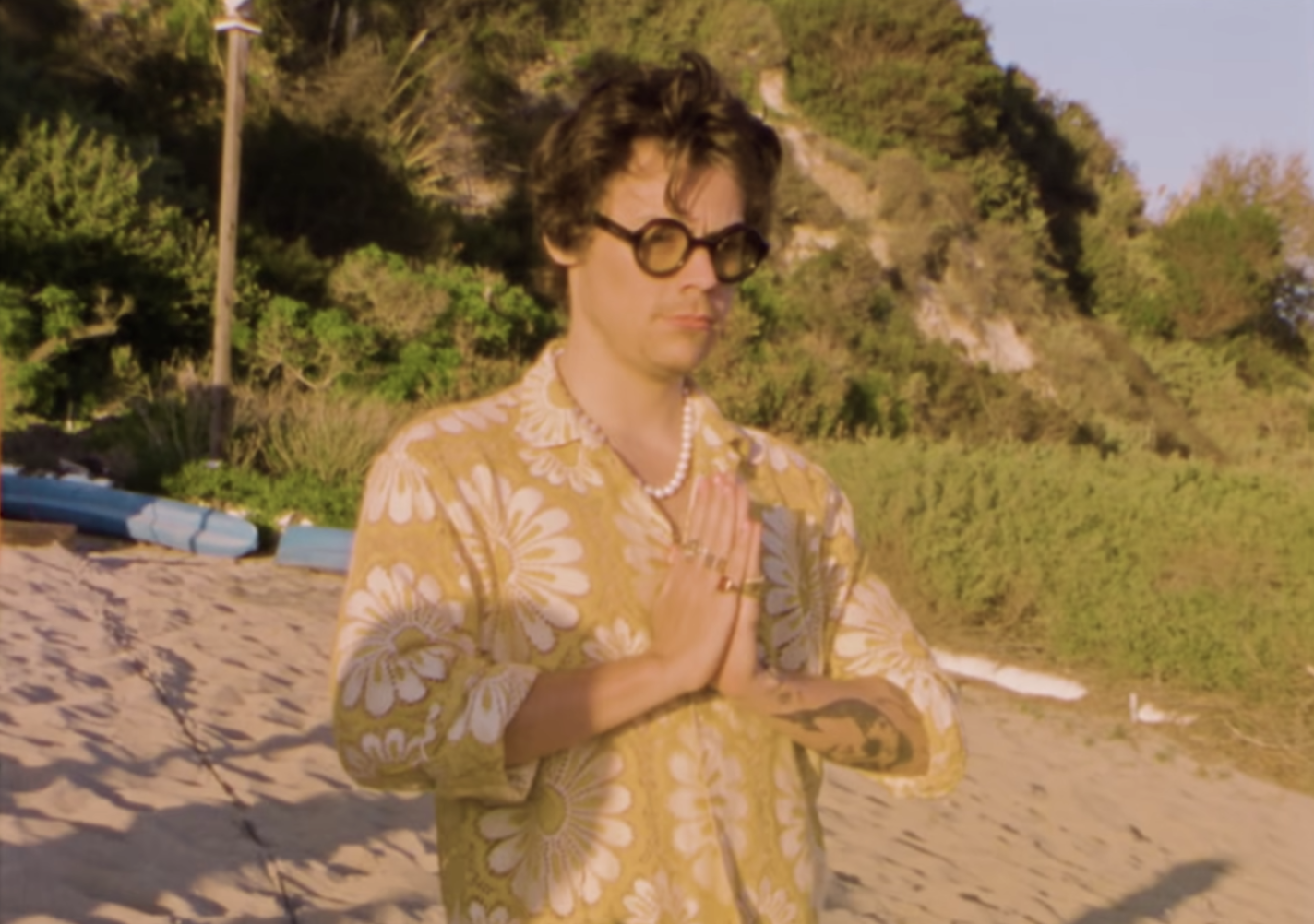 Harry meditating on the beach while clasping his hands in prayer