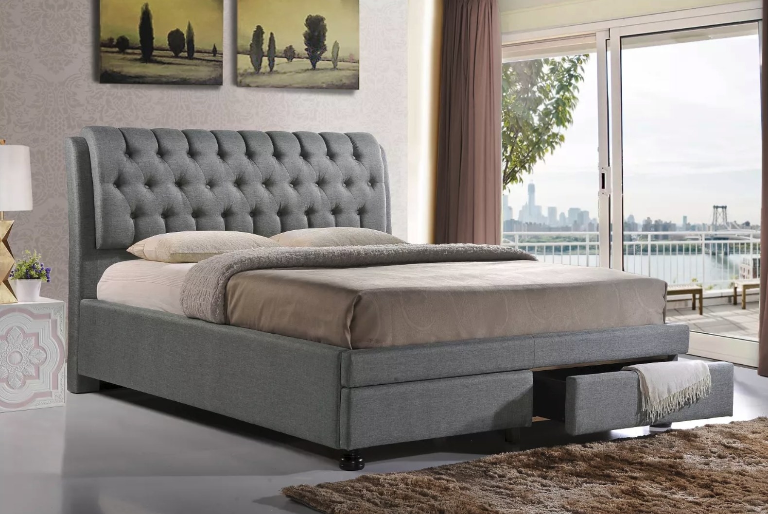 A gray bed frame with a tufted headboard and two drawers at the foot.
