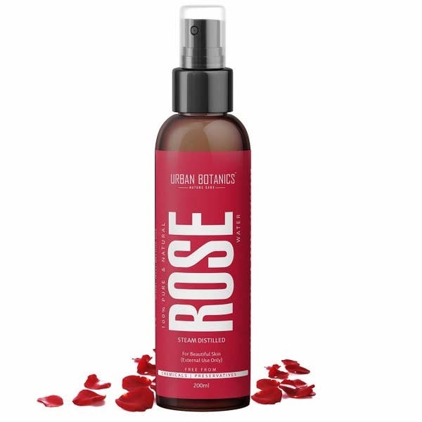 Bottle of the rose spray next to rose petals
