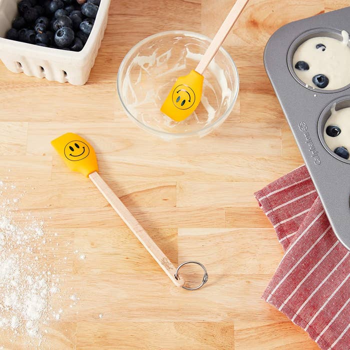 Two smiley face spatulas surrounded by baking supplies