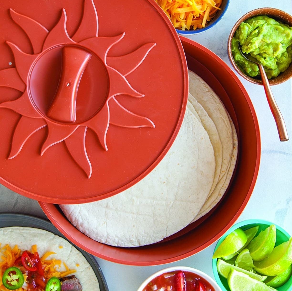 The tortilla warmer filled with flour tortillas and surrounded by condiments