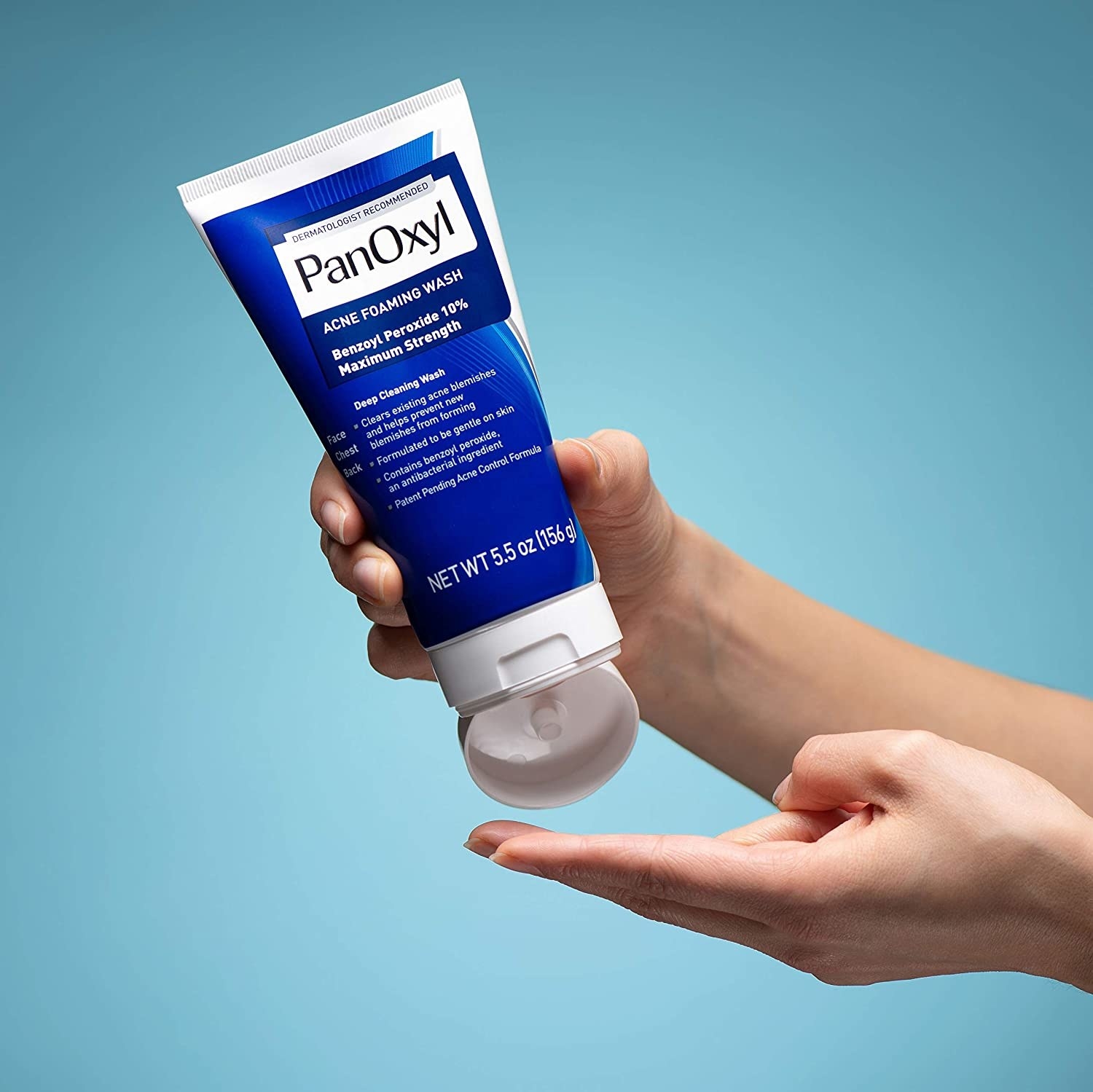 Product photo showing hands squeezing the PanOxyl acne foaming wash out of the bottle 