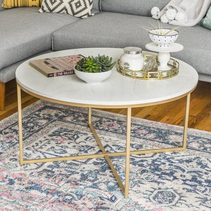 a round faux white marble coffee table with gold legs