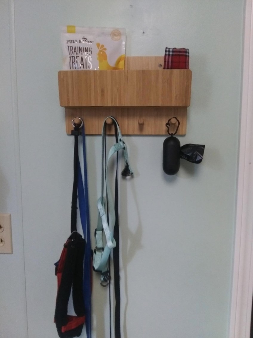 Reviewer&#x27;s image of the storage wall mount holding keys, leashes, poop bags, and treats