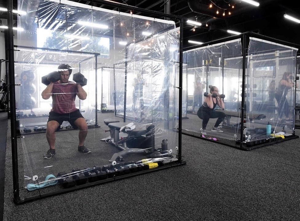 People working out in plastic cubicles at a gym