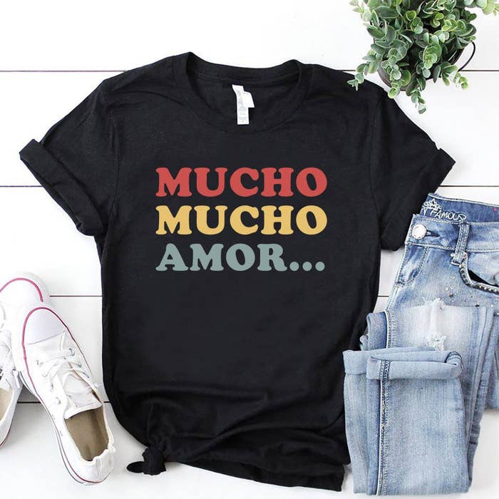 A black t-shirt with the words &quot;Mucho mucho amor&quot; in red, yellow, and green