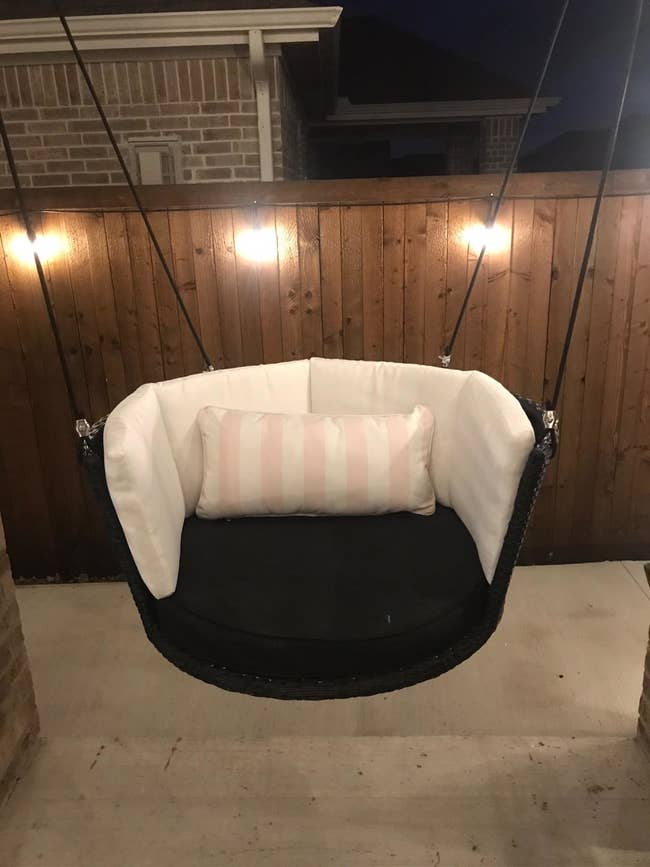 Reviewer photo of the swing, which has a thick cushion, a high back and comes with a pink and white striped lumbar pillow