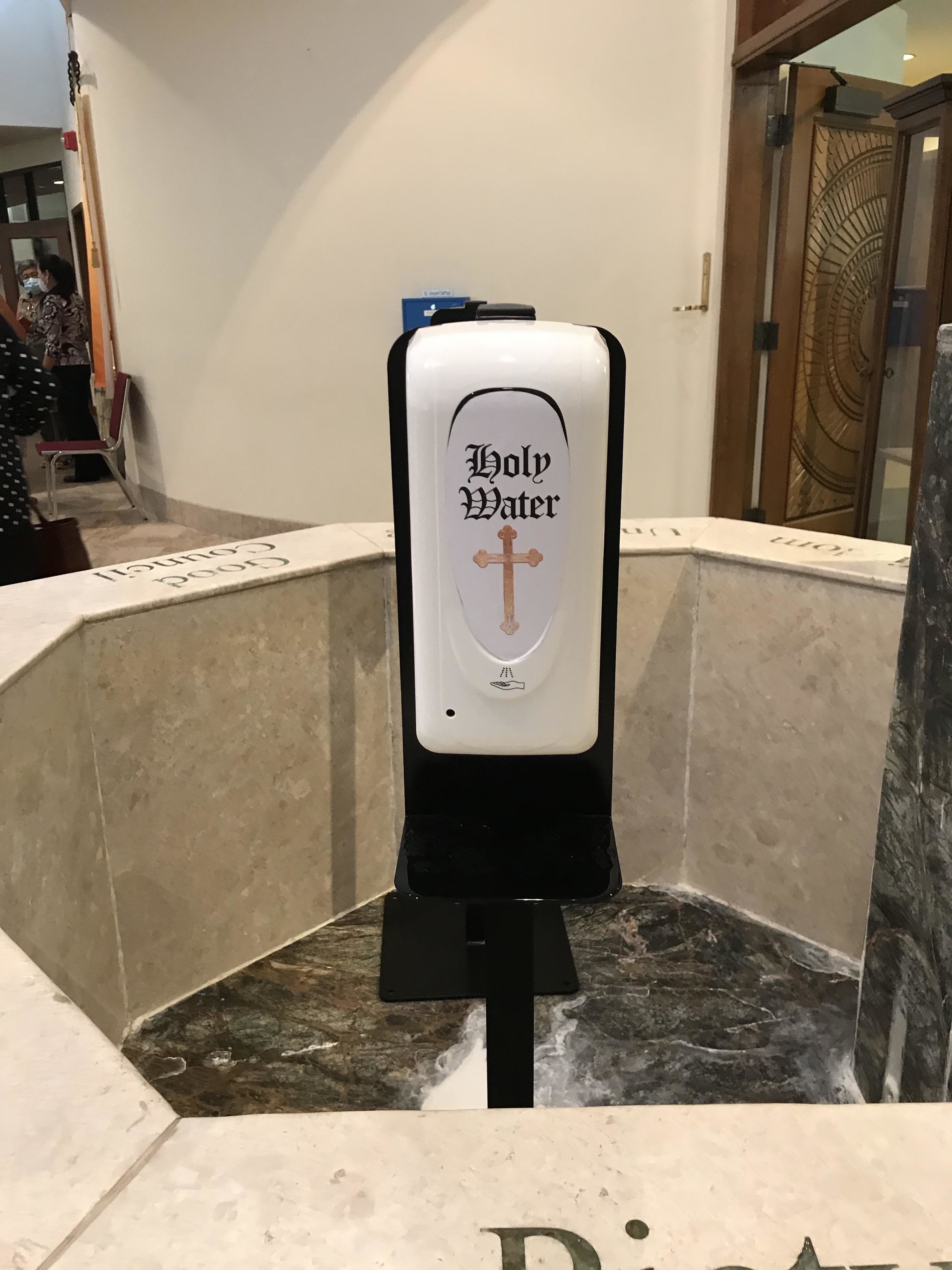 a hand sanitizer dispenser labeled Holy Water