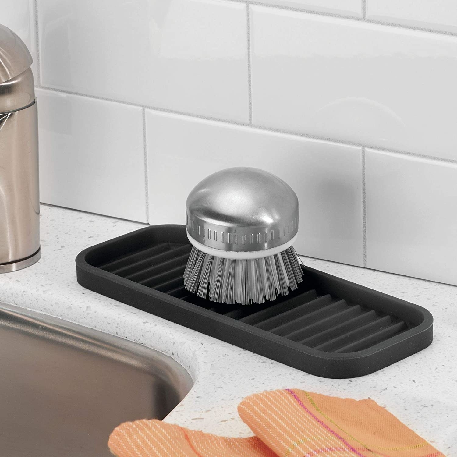 A scrub brush on top of the silicone kitchen sink tray