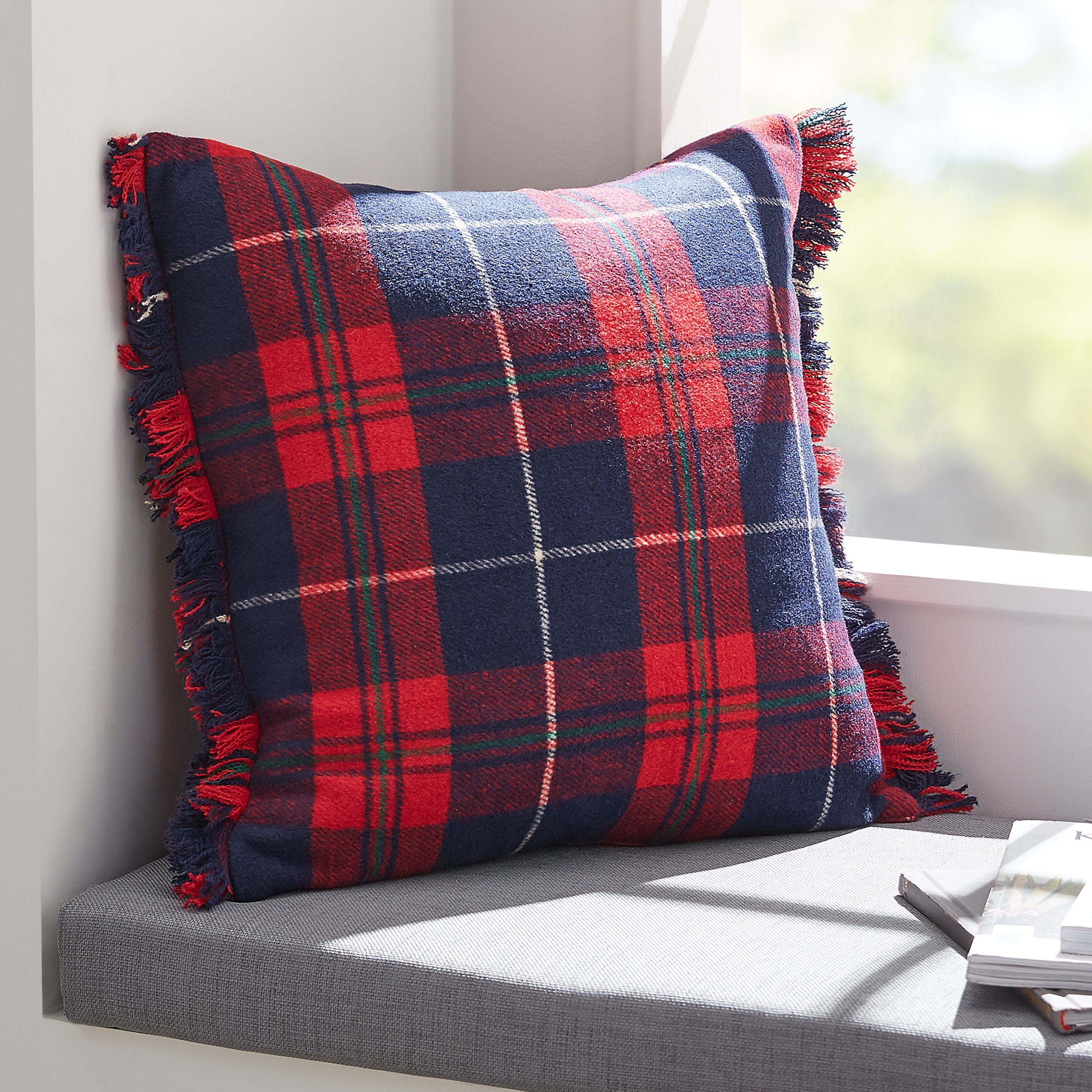 red and navy plaid pillow near a window