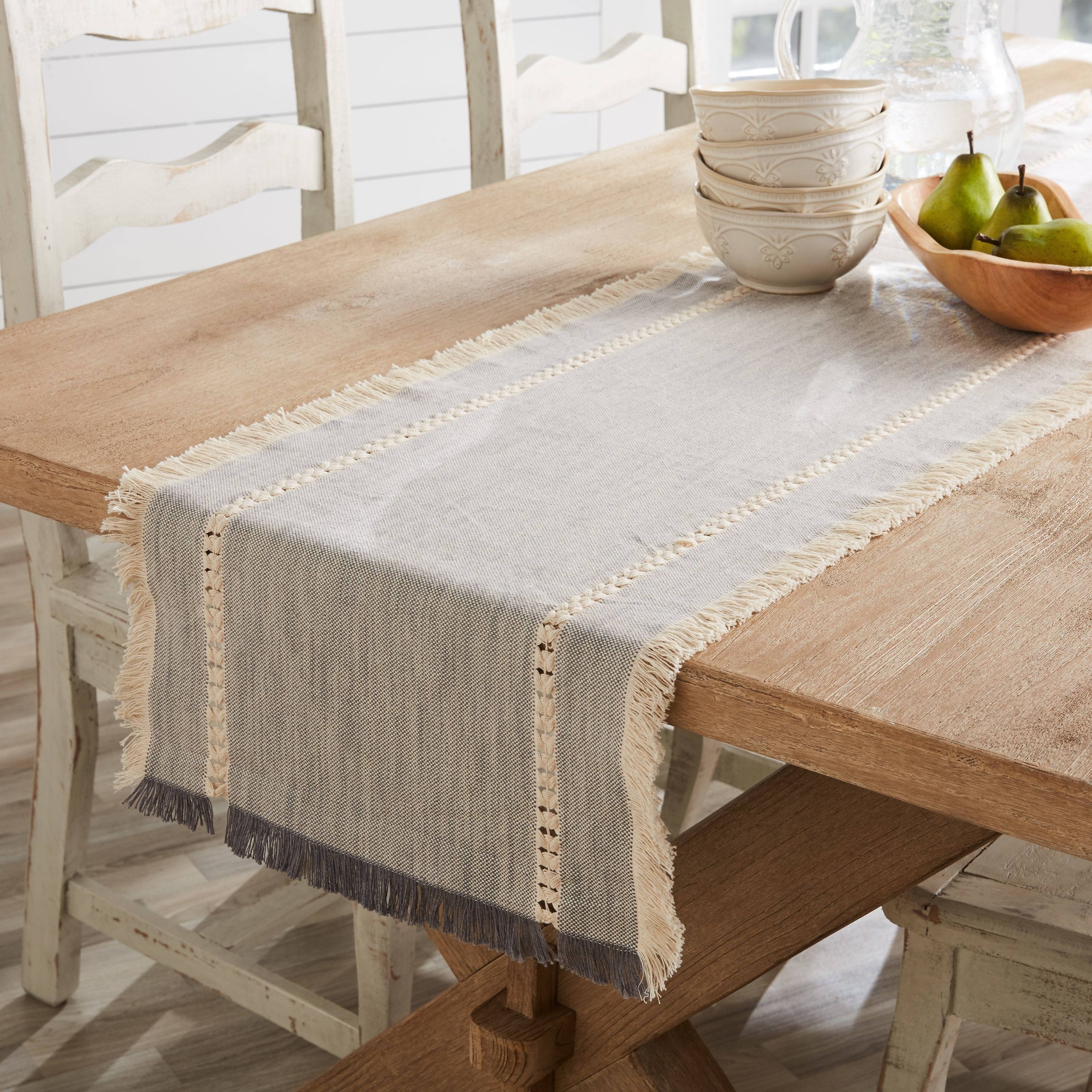 Grey table runner with beige tassels on a wooden dining room table