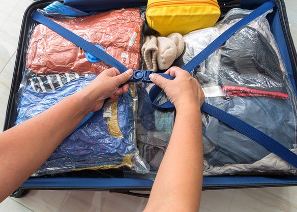 Hands close a very organized suitcase