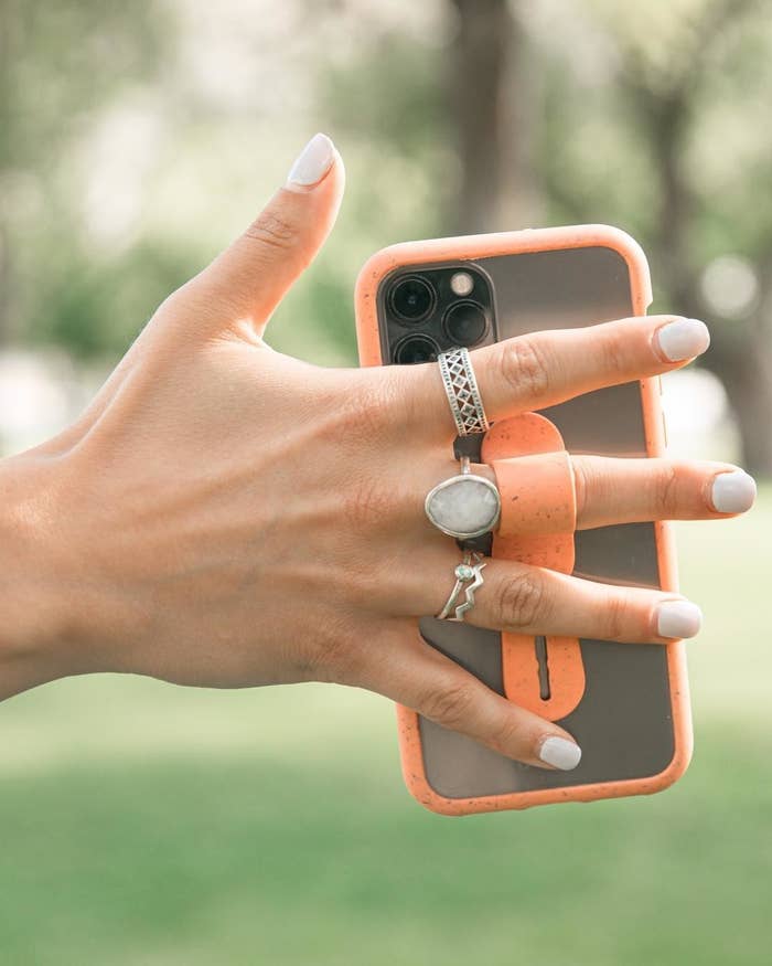 A person wearing several rings and holding their phone with the phone grip