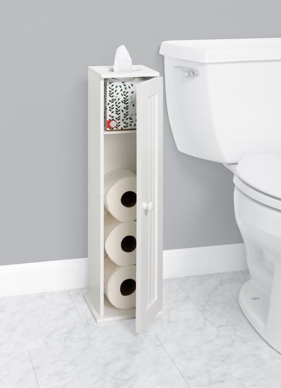 A white storage cabinet holding three rolls of toilet paper and a box of tissues