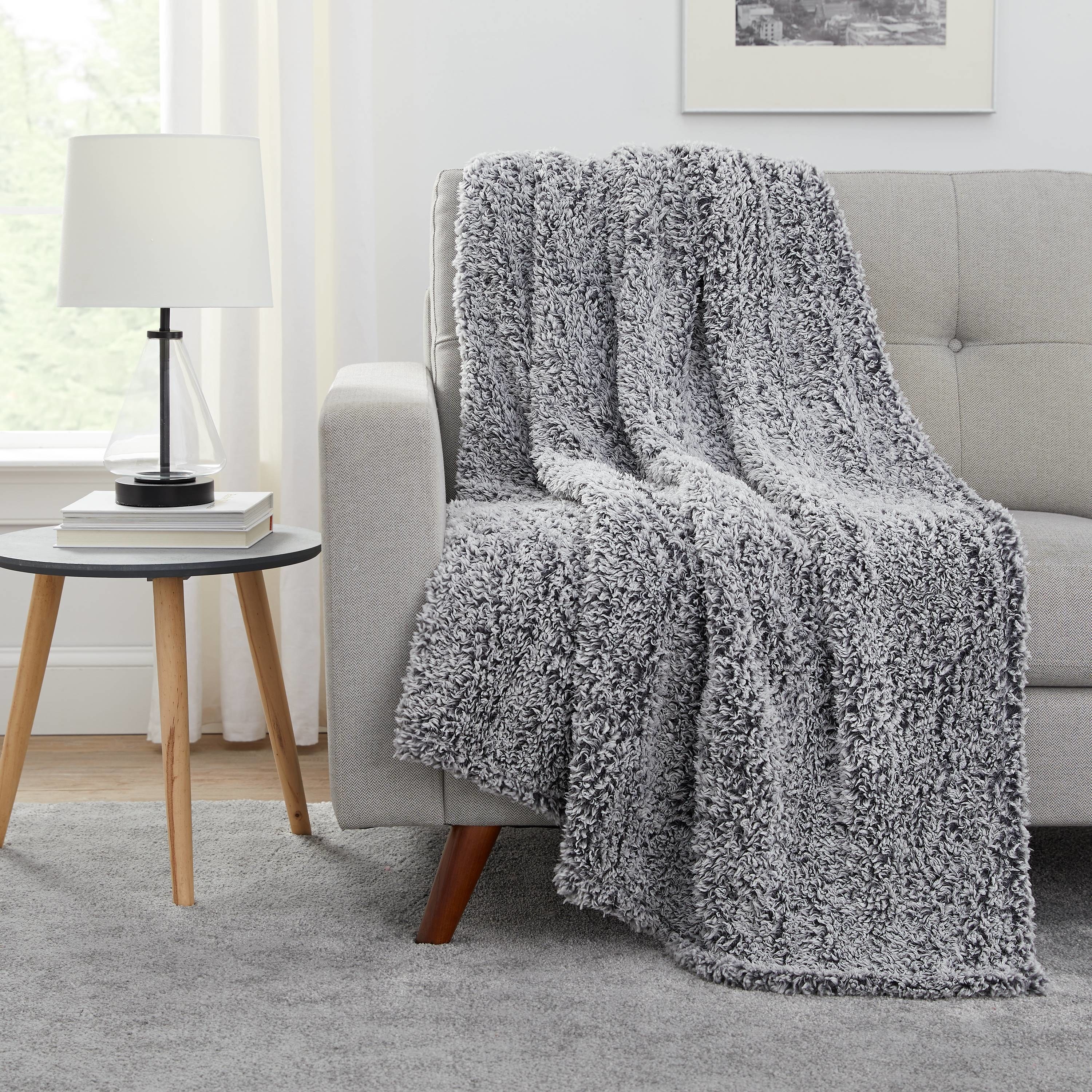 A grey sherpa blanket draped over a couch