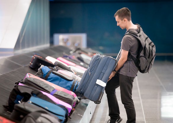 A man pulls a suitcase from a line of bags at baggage claim
