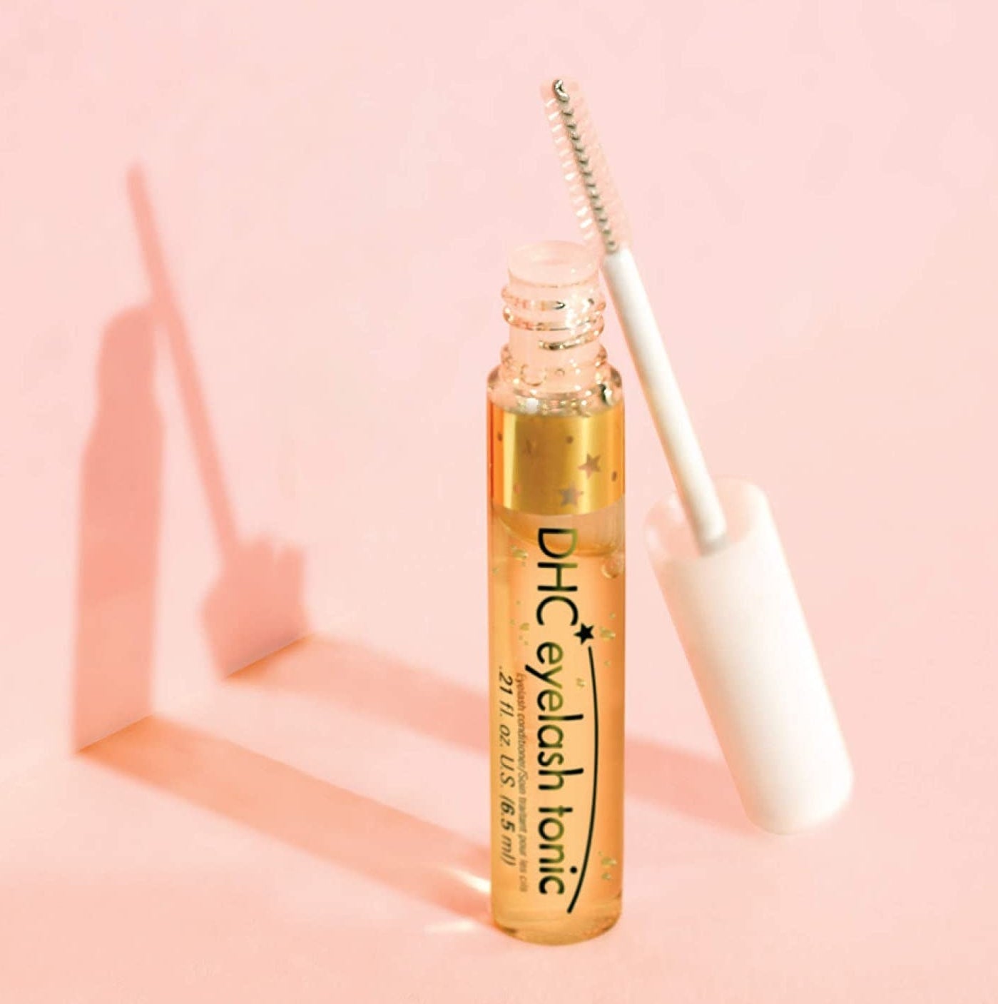 A tube of eyelash tonic with its wand leaning on its side