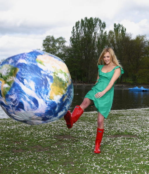 woman in red wellington boots and green dress kicking an inflatable earth.