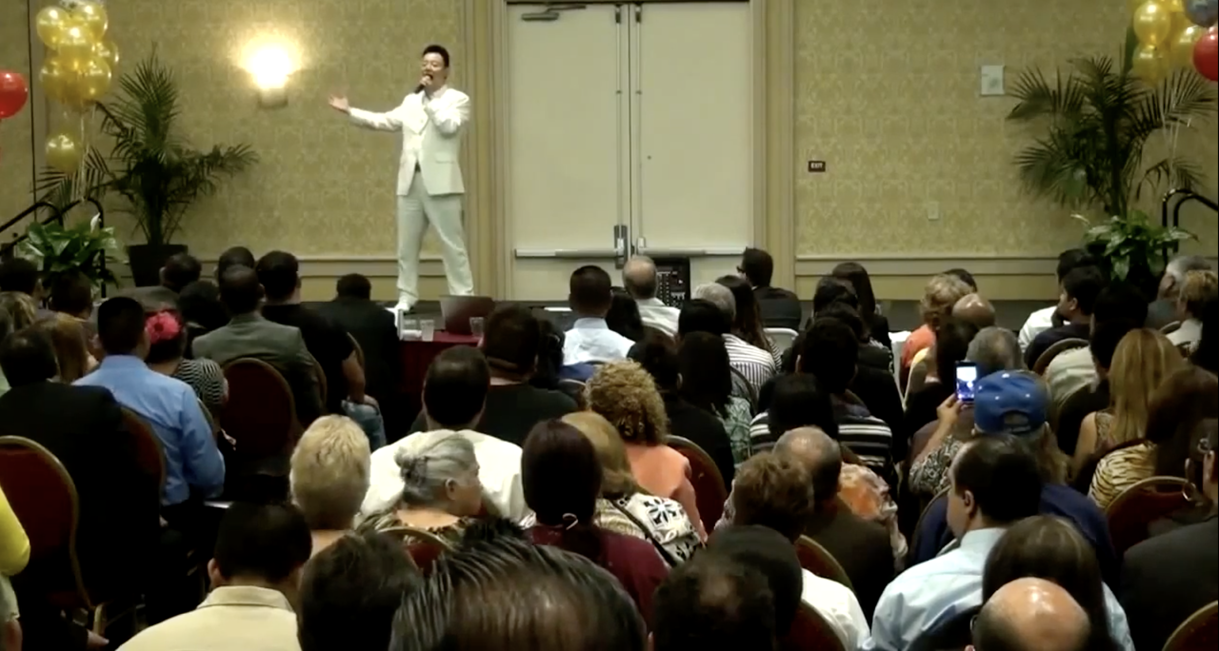 Xu speaking onstage wearing a white suit