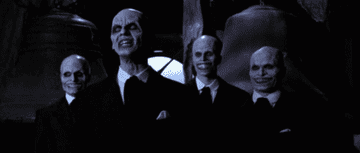 a bunch of men in suits and creepy alien faces nodding and clapping