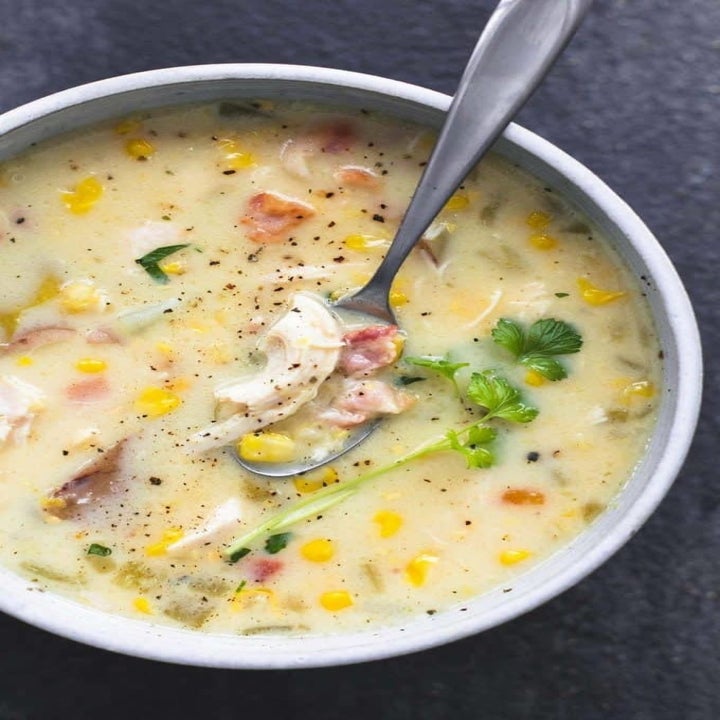 A bowl of corn and chicken chowder with fresh herbs on top.