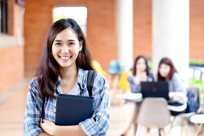 A college student smiling with friends in the background