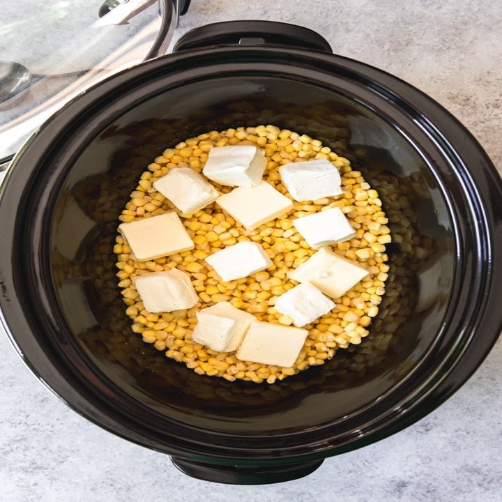 Corn kernels and chunks of butter in a slow cooker.