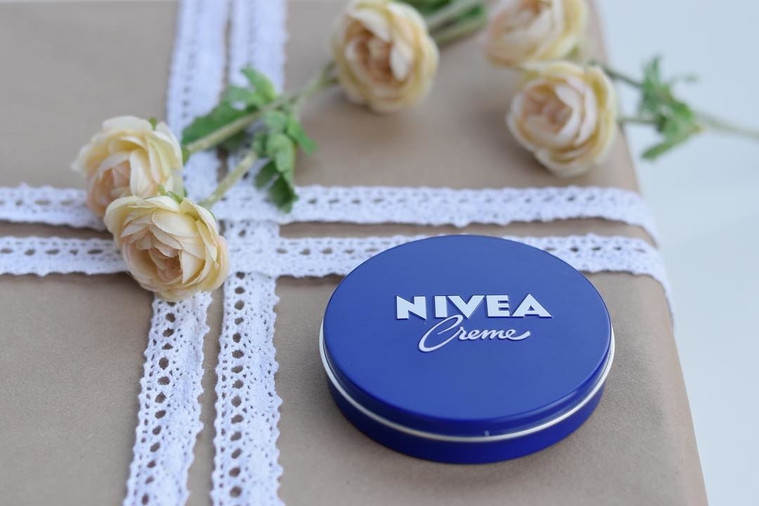 A tin of hand cream sitting on a wrapped gift with flowers
