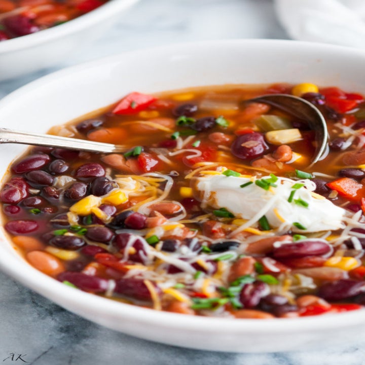 A bowl of bean chili with melted cheese and sour cream on top.
