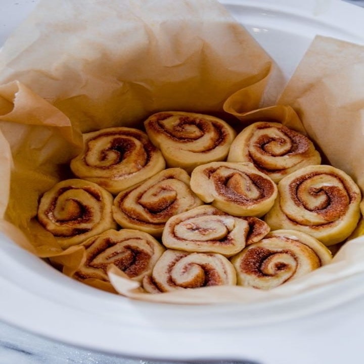Uncooked cinnamon rolls in a slow cooker with a liner.