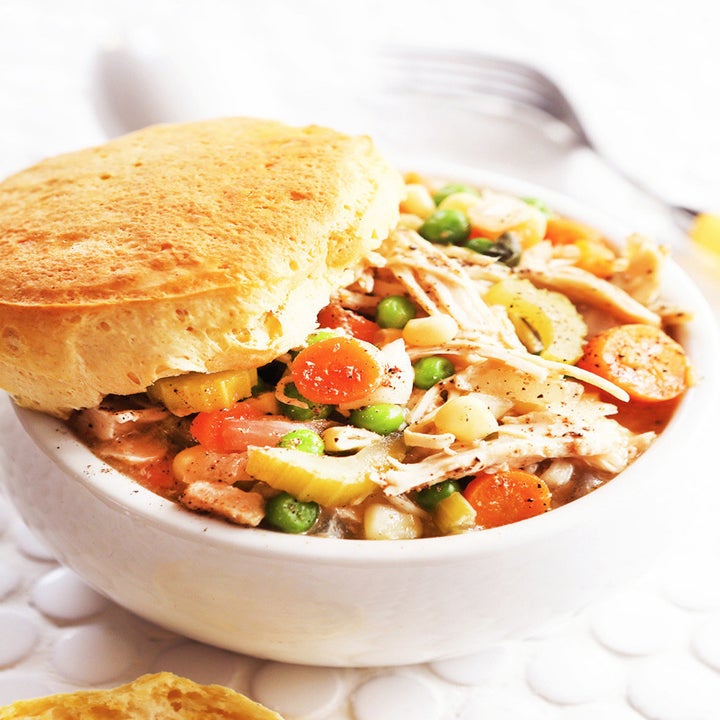 A bowl of chicken pot pie topped with a biscuit.