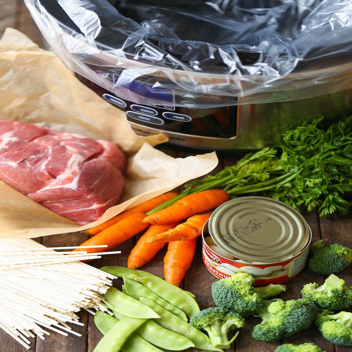 Ingredients for lo mein including snap peas, pork shoulder, carrots, broccoli, noodles, and herbs.
