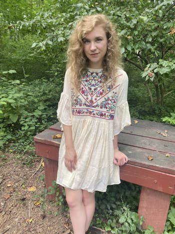 BuzzFeed writer in a white dress with an embroidered floral pattern on the chest 