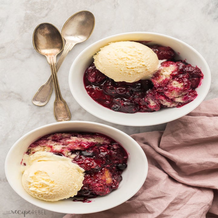 Two bowls of berry cobbler topped with a scoop of vanilla ice cream.