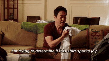 A GIF of someone holding a shirt and saying I&#x27;m trying to determine if this shirt sparks joy
