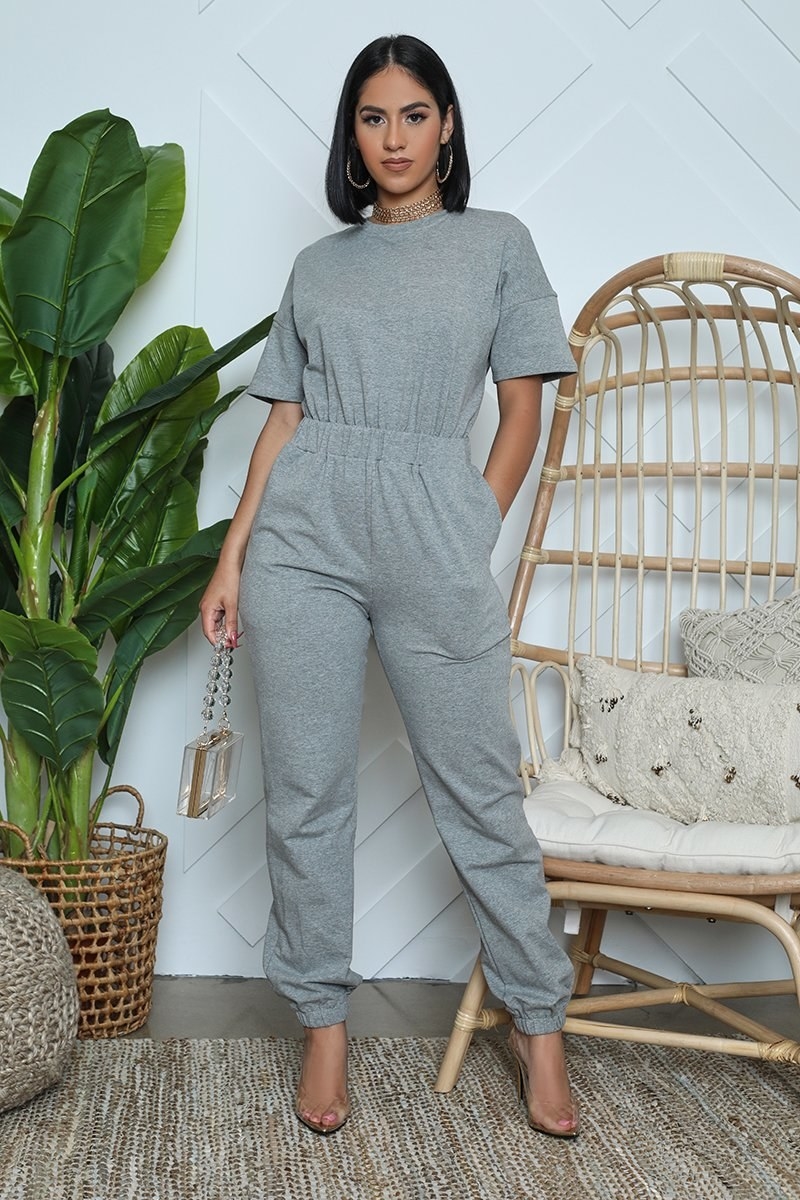 A model in a gray sweat jumpsuit with an elastic waist