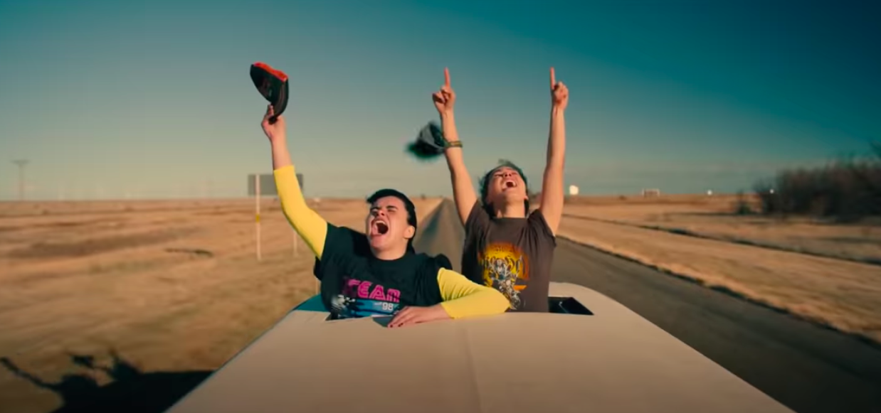 The teens yell in joy from a sunroof of a car