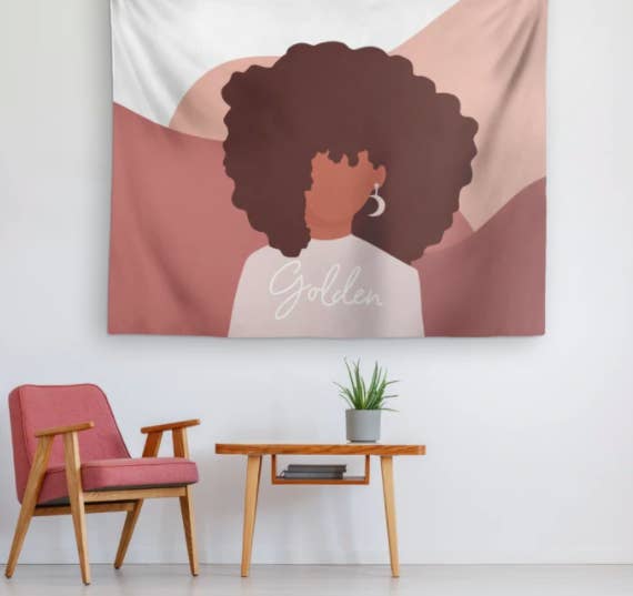 Pink, brown, and white patterned tapestry with a woman wearing moon earrings and a shirt that says 