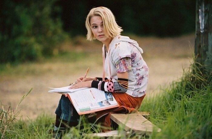 Leslie sitting on a wooden bench, doing her homework