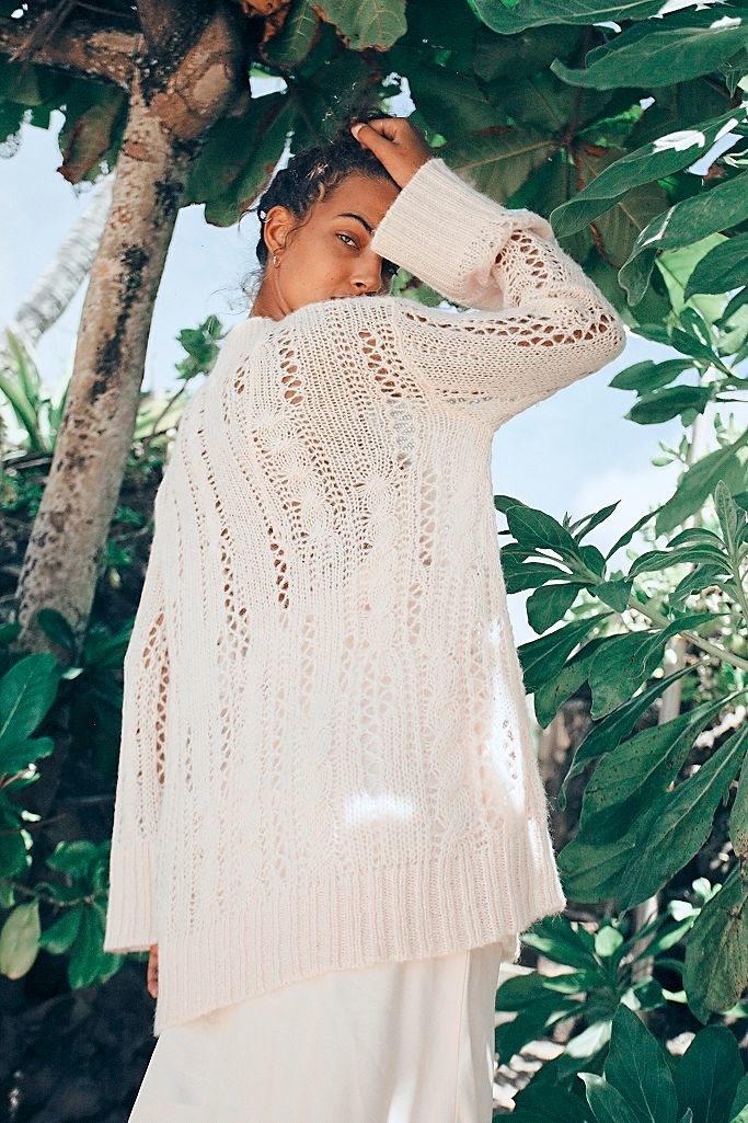 A model wears a camisole midi slip dress underneath a loose oversized knitted sweater with large enough holes that it&#x27;s see through