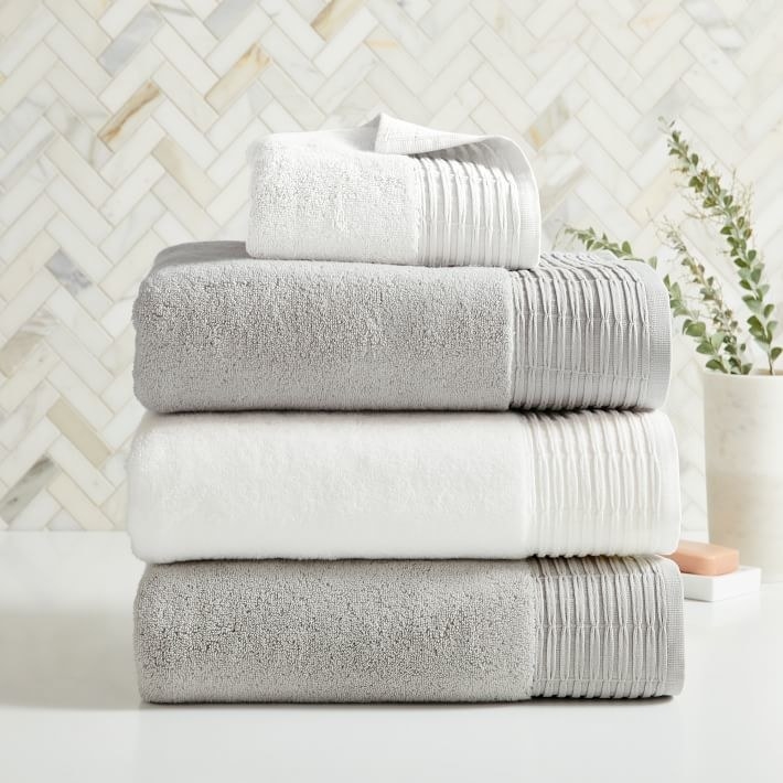 A stack of grey and white towels with pleated decorative edge