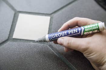 Model's manus holding a bluish and greenish grout pen