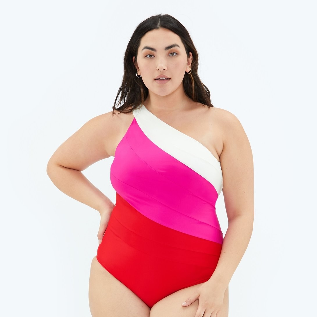model wearing red, pink, and white one-shoulder swimsuit