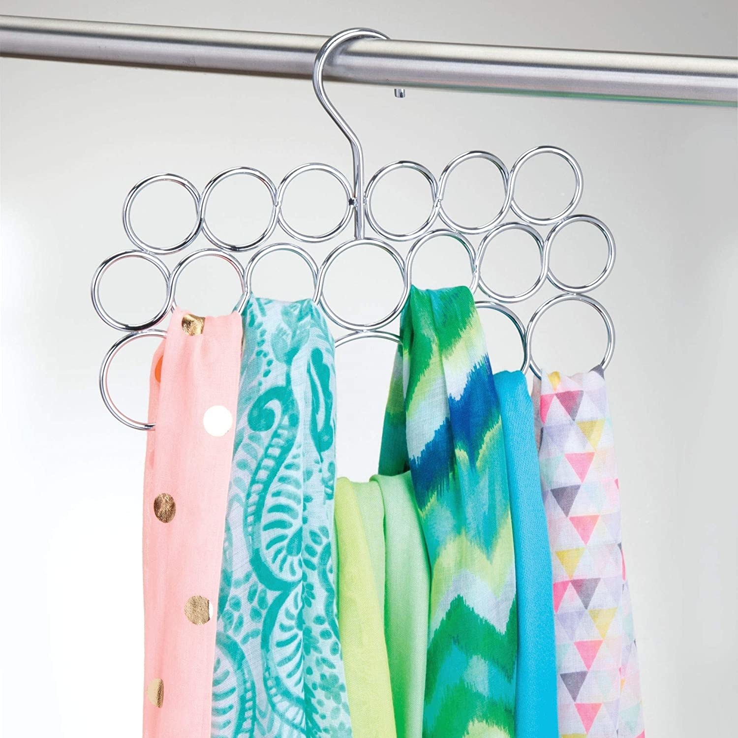 A metal hanger with a dozen small circles Colourful scarves are hanging from the loops