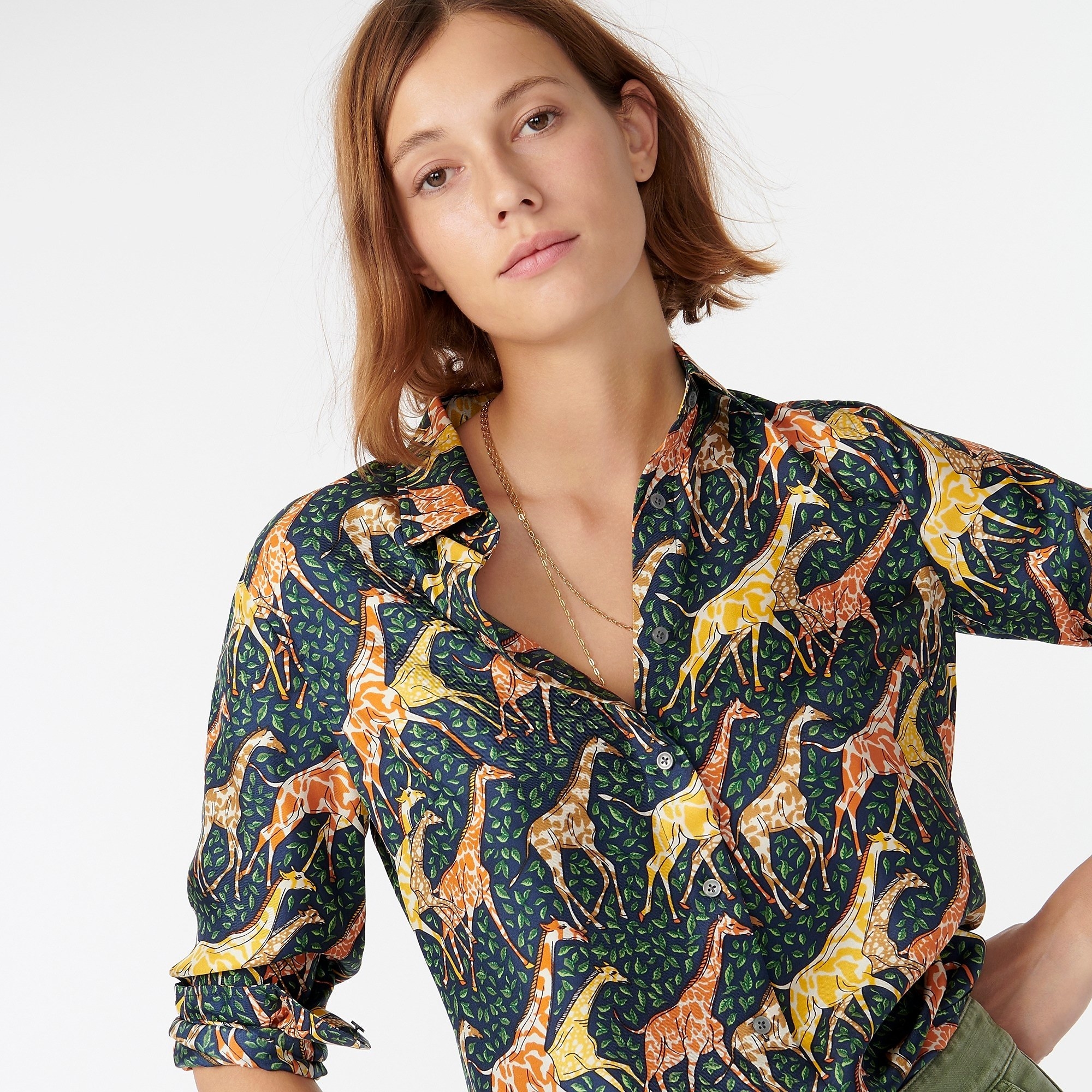 A model wearing the navy shirt printed with green leaves and a heard of yellow and orange running giraffes