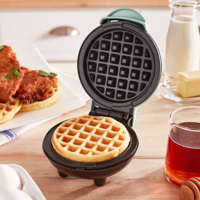 The waffle iron being used to make chicken and waffles