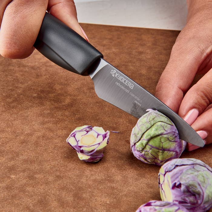 Person cutting Brussels sprouts in half with knife